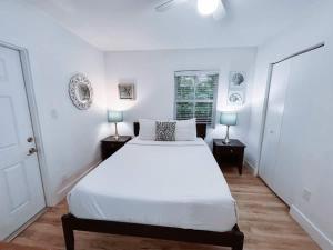 a white bedroom with a large bed and two lamps at Beach Getaway One Block from the Beach in Pompano Beach