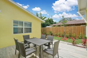 a patio with a table and chairs and a fence at Beach Getaway One Block from the Beach in Pompano Beach