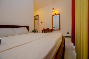 a bedroom with a white bed and a mirror at Happy Corner Ahangama in Midigama West