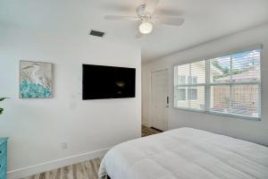 a white bedroom with a bed and a flat screen tv at Beach Escape One Block from the Beach in Pompano Beach