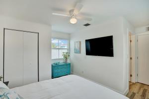 a bedroom with a bed and a flat screen tv at Beach Escape One Block from the Beach in Pompano Beach