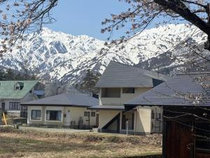 una casa di fronte a una montagna innevata di 涼亭 川 Ryoutei Kawa a Hakuba