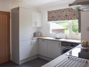 a kitchen with white cabinets and a window at Lilybank Cottage in Doularg +15 photos