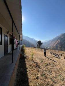 a group of people walking in a field next to a building at Yashraj Cottages in Jari