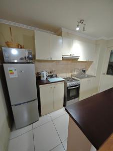 een keuken met witte kasten en een koelkast bij Cómodo alojamiento 3D 1B excelente ubicacion in Temuco