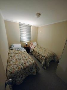 twee bedden in een kleine kamer met een raam bij Cómodo alojamiento 3D 1B excelente ubicacion in Temuco