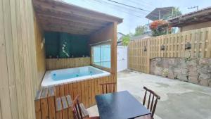 a hot tub on a patio with a table and chairs at Casa com jacuzzi in Florianópolis