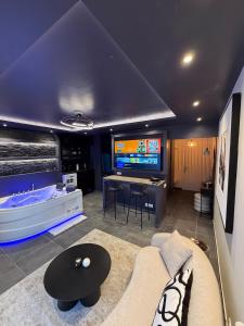 a living room with a couch and a tv at L'Écrin Beige - Immersive suite with private Jacuzzi in Champlan