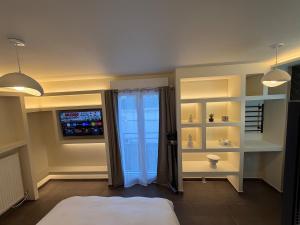 a bedroom with a bed and a tv and a window at L'Écrin Beige - Immersive suite with private Jacuzzi in Champlan