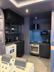 a kitchen with black cabinets and stainless steel appliances at L'Écrin Beige - Immersive suite with private Jacuzzi in Champlan
