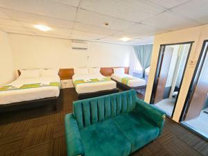 a room with two beds and a green couch at Hotel Ma'Wa Kota Bharu in Kota Bharu