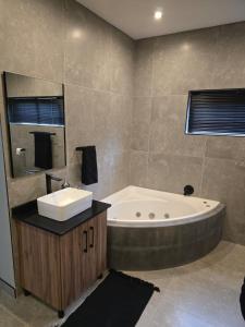 a bathroom with a sink and a bath tub at Crane's Nest - Luxury Ground in Pretoria +8 photos