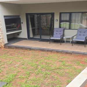 two purple chairs sitting on a patio with a fireplace at Crane's Nest - Luxury Ground in Pretoria