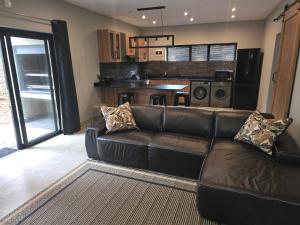 a living room with a leather couch and a kitchen at Crane's Nest - Luxury Ground in Pretoria