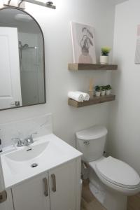 een badkamer met een toilet, een wastafel en een spiegel bij Sunny Suite in Saskatoon