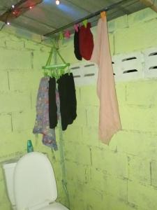 a bathroom with a toilet and clothes hanging on a wall at Easy Life Hut in Ko Bu Bu