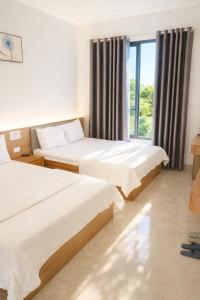 een hotelkamer met twee bedden en een raam bij Visip Hotel in Vinh