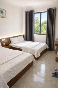 een hotelkamer met twee bedden en een raam bij Visip Hotel in Vinh