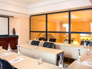 een restaurant met tafels en stoelen en grote ramen bij Mercure Johannesburg Midrand in Midrand