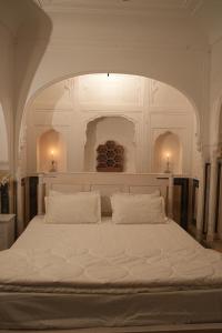 a bedroom with a large white bed with two pillows at Bagru Haveli in Jaipur +4 photos