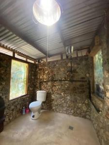 ein Badezimmer mit Toilette und Steinwand in der Unterkunft Serene and peaceful farmstay near Xaibe in Corozal