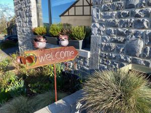 杜柏B&B l'Aigrin的花园里摆放着盆栽植物，旁边立着一块欢迎牌。 更多32张照片