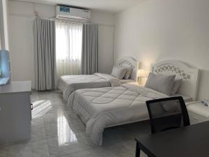 ein Hotelzimmer mit zwei Betten und einem Tisch in der Unterkunft Furnished 2BR Central Al Ain in al-Ain