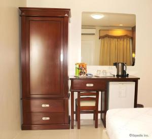 een slaapkamer met een dressoir en een bureau met een spiegel bij Devera Hotel in Angeles