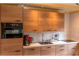 een keuken met houten kasten en een spoelbak bij Lovely Holiday Home in Texel near Sea in Oost