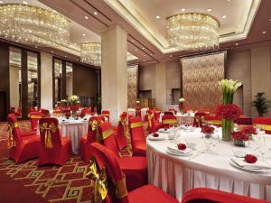 einen Bankettsaal mit weißen Tischen und roten Stühlen in der Unterkunft Grand Mercure Beijing Central in Peking