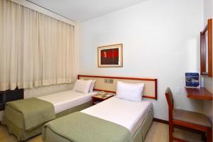 a hotel room with two beds and a chair at Boulevard Express in Belo Horizonte