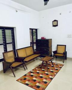 a living room with two chairs and a table at HARSHAM Eco Village in Puthuppādi