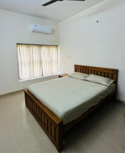 a bedroom with a wooden bed in a room with a window at HARSHAM Eco Village in Puthuppādi
