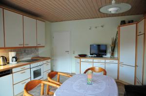 eine Küche mit einem Tisch und Stühlen sowie einem TV in der Unterkunft Ferienwohnung Noviomagus in Neumagen-Dhron