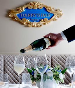 
a person holding a wine glass next to a sign at Harry's Bar Trevi Hotel & Restaurant in Rome
