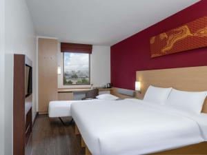 a hotel room with a large white bed and a window at Ibis Bangkok Riverside in Bangkok