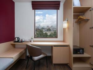 a room with a desk and a window at Ibis Bangkok Riverside in Bangkok