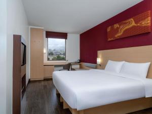 een hotelkamer met een groot wit bed en een raam bij Ibis Bangkok Riverside in Bangkok +55 foto's