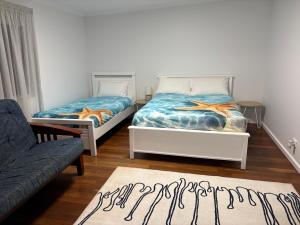 two beds in a room with a couch and a rug at Rustic Retreat Esperance in Esperance