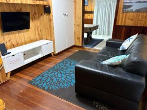 a living room with a black leather couch and a tv at Rustic Retreat Esperance in Esperance