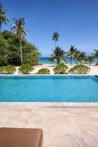 una piscina di fronte a una spiaggia con palme di Le Baoli Koh Rong a Phumĭ Kaôh Rŏng