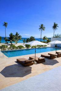 una piscina con lettini e ombrelloni di Le Baoli Koh Rong a Phumĭ Kaôh Rŏng