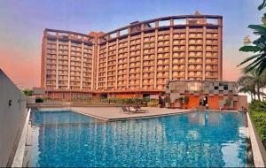 a hotel with a large pool in front of a building at Magiical weekend in Surat