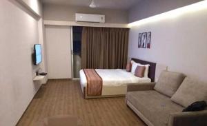 a hotel room with a bed and a couch at Magiical weekend in Surat