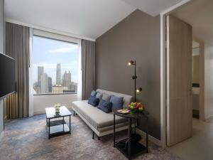 een woonkamer met een bank en een groot raam bij Mercure Bangkok Siam in Bangkok