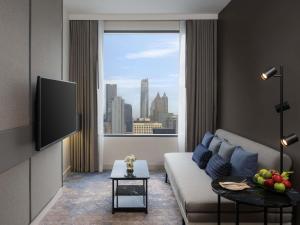 a living room with a couch and a large window at Mercure Bangkok Siam in Bangkok
