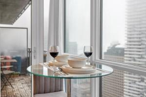 a glass table with two glasses of wine on it at Luxe 3-Bedroom Lakeview Condo, Free parking ,Walk to CN Tower, Scotiabank Arena & Rogers Centre in Toronto