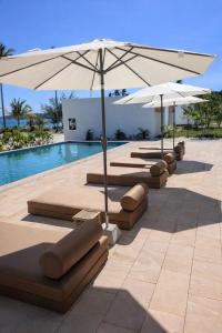 una fila di chaise longue e ombrelloni accanto a una piscina di Le Baoli Koh Rong a Phumĭ Kaôh Rŏng