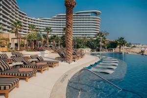 ein Resortpool mit Liegestühlen und ein Hotel in der Unterkunft Waldorf Astoria Doha Lusail in Doha
