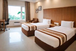 ein Hotelzimmer mit zwei Betten und einem Schreibtisch in der Unterkunft La Franklin Hotel in Bhubaneshwar